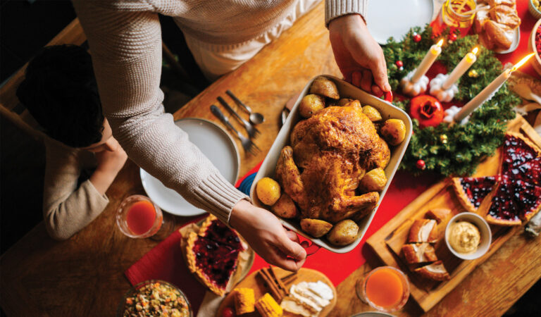 Thanksgiving table with a person carrying a turkey, practicing fire safety.