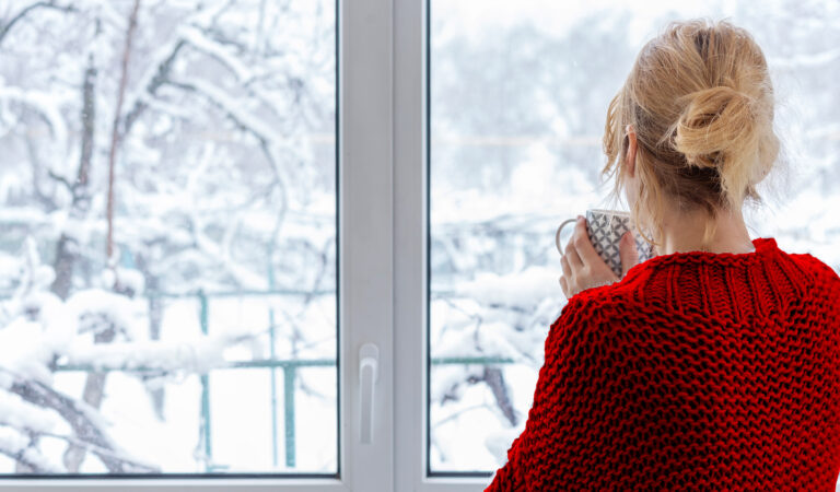 Woman Looking out at Snowy Backyard